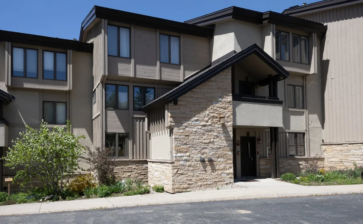 The image showcases the front entrance of the property, featuring a welcoming stone facade, well-kept landscaping, and a pathway leading to the door. The inviting exterior hints at accessible entry and the ability to come and go easily for both daily routines and adventure.